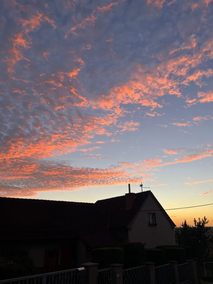 Růžové mraky při západu slunce nad domem